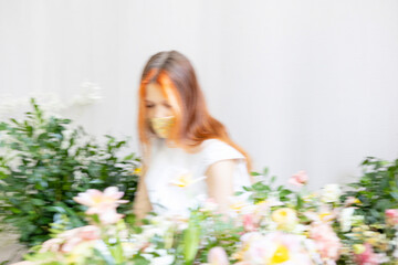 Obraz na płótnie Canvas blurred in motion portrait of red haired teen girl among the flowers