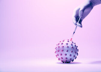 Vaccination against coronavirus. A conceptual representation of the coronavirus vaccination process. The syringe with the vaccine in the doctor's hand. On a pink background, tinted in light pink