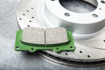 brake pads and perforated brake discs on a stone gray table
