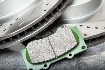 brake pads and perforated brake discs on a stone gray table