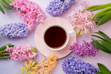 Obraz na płótnie Canvas A cup of tea with flowers hyacinths on a pink-lilac background. Idea. spring background, concept. Top view.