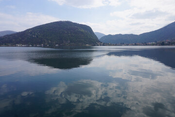 mirror reflection of puffy white clouds in lake Lugano, Ticino