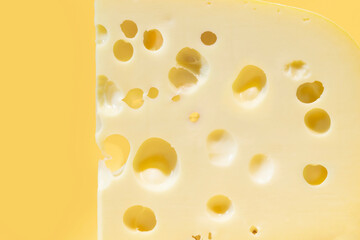 Close-up of gruyere cheese isolated on yellow background.
