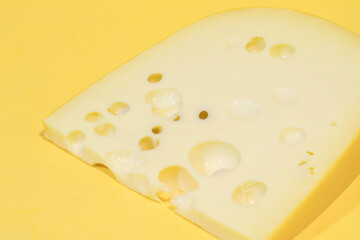 Close-up of gruyere cheese isolated on yellow background.