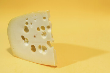 Close-up of gruyere cheese isolated on yellow background.