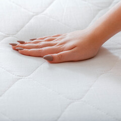 Choice comfortable mattress for sleep in store. Quality control hardness of white mattress. Woman choosing new mattress. Female hand Pressing Testing mattress to Check softness. square