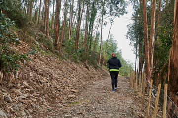 Rear view of young female runner running up hillside track