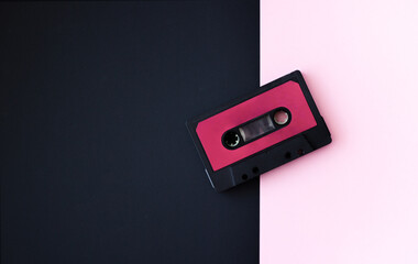 Black music cassette on pink black background. Space for text. Retro concept