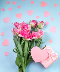 Romantic background with bouquet of tulips and gift boxes on blue surface. Top view with copy space.