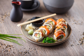 Sushi maki rolls with salmon, eel, avocado, cucumber on a plate with chopsticks, soy sauce, wasabi...