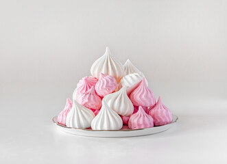 White and pink meringues on a porcelain plate.