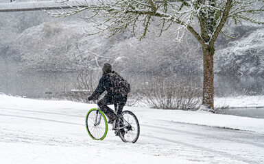 Duringa snow storm, a man riding a bicycle in riverfront park, salem, Oregon