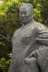 Shanghai, China - May 4, 2010: Facial closeup of  Chen Yi gray statue. Green foliage as backdrop. 
