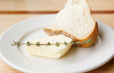 Bread and butter slices garnished with thyme are a simple, fresh appetizer presented against a rustic wooden background.
