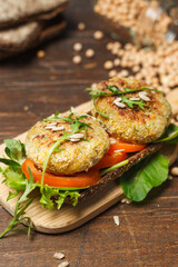 Sandwich on rye bread with chickpea cutlet, tomatoes and lettuce, on a wooden board. Close-up, focus in the foreground.