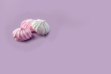 Obraz na płótnie Canvas Pink and white meringue on a purple background. Place for your text. High quality photo