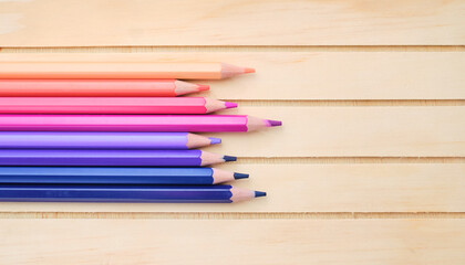 Fototapeta premium Composition with pink, purple and blue pencils on wood background, top view