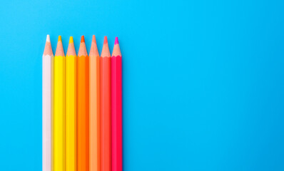 Composition with colored pencils on blue background, top view