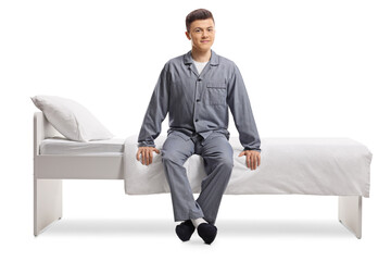 Young man in pajamas sitting on a single bed
