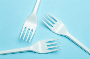 Plastic forks on a blue background. Plastic waste and pollution concept
