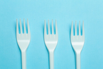 Plastic forks on a blue background. Plastic waste and pollution concept