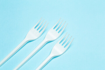 Plastic forks on a blue background. Plastic waste and pollution concept
