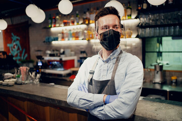 Fototapeta na wymiar A male barista brews and sells coffee to take away. Paper cup with a drink Americano, espresso, cappuccino. Protective mask on the face from the virus, pandemic, flu.