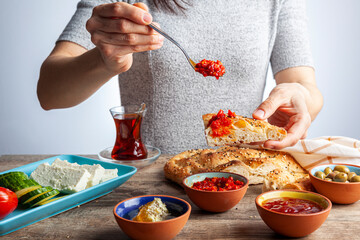 Healthy Turkish breakfast, with sliced tomato, cucumber, and white feta cheese, small bowls of strawberry jam, olive, honey, pepper paste. Tea is served in traditional Turkish tea glass. Ramadan feast