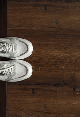 White sneakers on the wooden floor in two colors. Top view.
