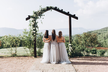 Bridesmaids in white dresses on the green grass against the backdrop of the mountains.