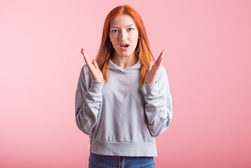 Fototapeta premium Young redhead girl shocked in studio on pink background