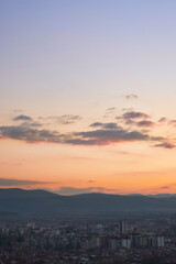 Stunning blue hour view of a city with colorful buildings, burning sky and background horizon mountains