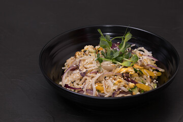 Plate of wok salad with vegetables, on a black background