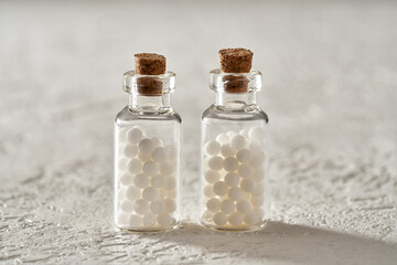 Two bottles of homeopathic pills on a white background