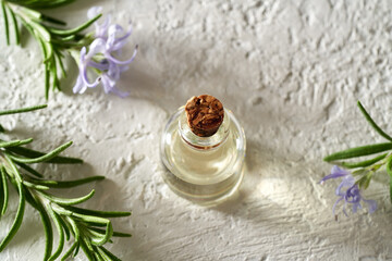 Obraz na płótnie Canvas A bottle of rosemary essential oil with fresh blooming rosemary