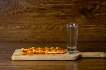 shot of white tequila and spicy orange slices on elegant wooden background