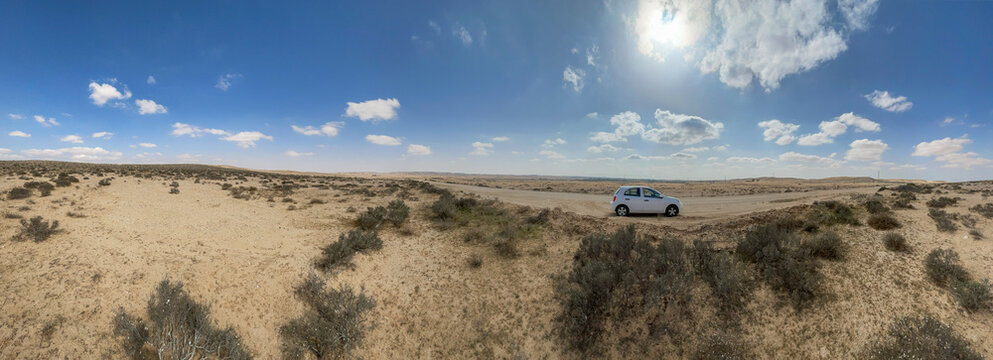 Abnormal wide panorama of the Negev desert with a small car
