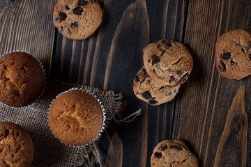 Morning breakfast vanilla muffins in white paper cups on a beautiful towel, close-up. Wooden background. 