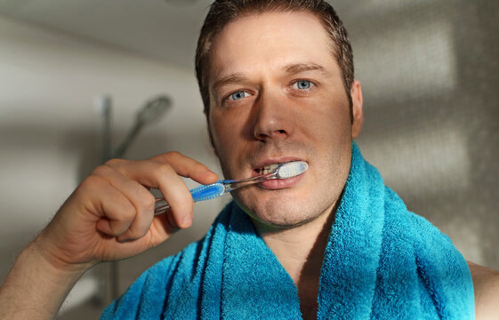 Man brushes his teeth in the bathroom.