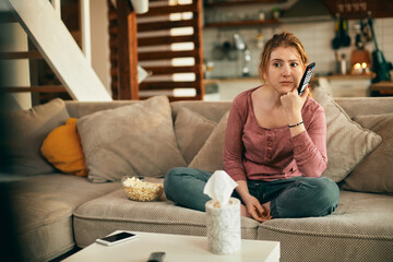 Obraz premium Young woman watching sad movie on TV in the living room.