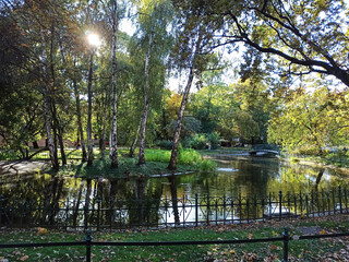 Wide angle of a pond in a park surrounded with trees in Planty Gardens against sunset in Cracow city of Poland, Europe