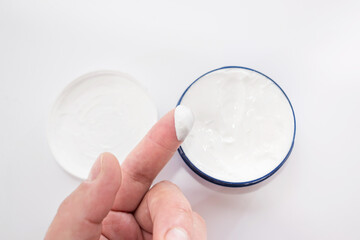 Female hands holding and apply jar of nourishing cream on white background.Skin care and beauty concept.