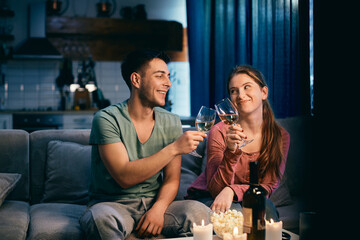 Young happy couple toasting with wine in the evening at home.