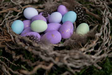 Multicolored easter eggs lie in the nest on the ground.