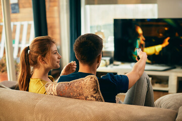 Young couple watching movie on TV at home.