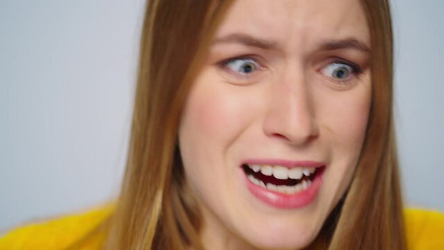 Closeup rage woman screaming at camera on grey background. Stressed female model