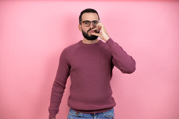 Handsome man wearing glasses and casual clothes over pink background with mouth and lips shut as...