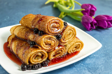 Pancakes with blueberries on a plate poured with jam. Close-up.