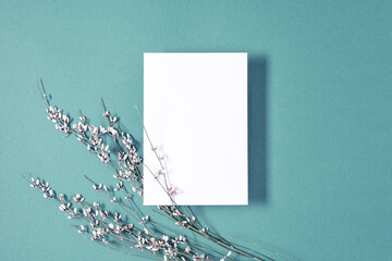 White paper empty blank, flowers on blue background. Invitation card mockup on white table. Flat...
