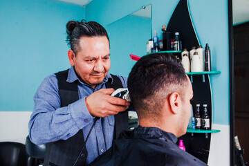 latin man stylist cutting hair to a client in a barber shop in Mexico